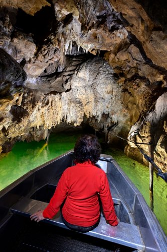 Grotte de Labouiche (Ariège) - Coulées de calcite au dessus de la rivière vues depuis un bateau avec personnage en rouge.(SP-23-1672)